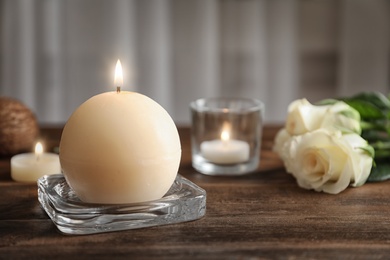 Photo of Glass stand with burning wax candle on wooden table