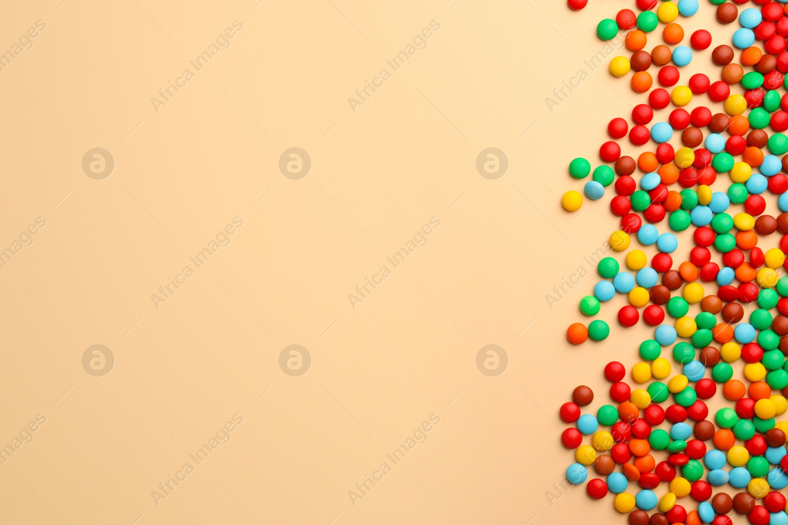 Photo of Tasty colorful candies on beige background, flat lay. Space for text