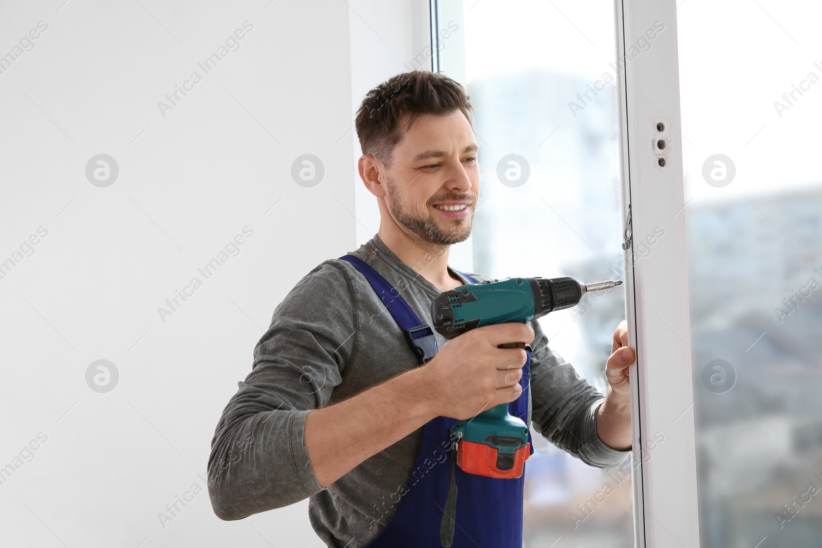 Photo of Construction worker using drill while installing window indoors