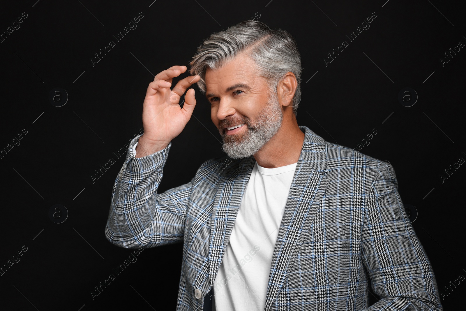 Photo of Portrait of smiling man with beautiful hairstyle on black background