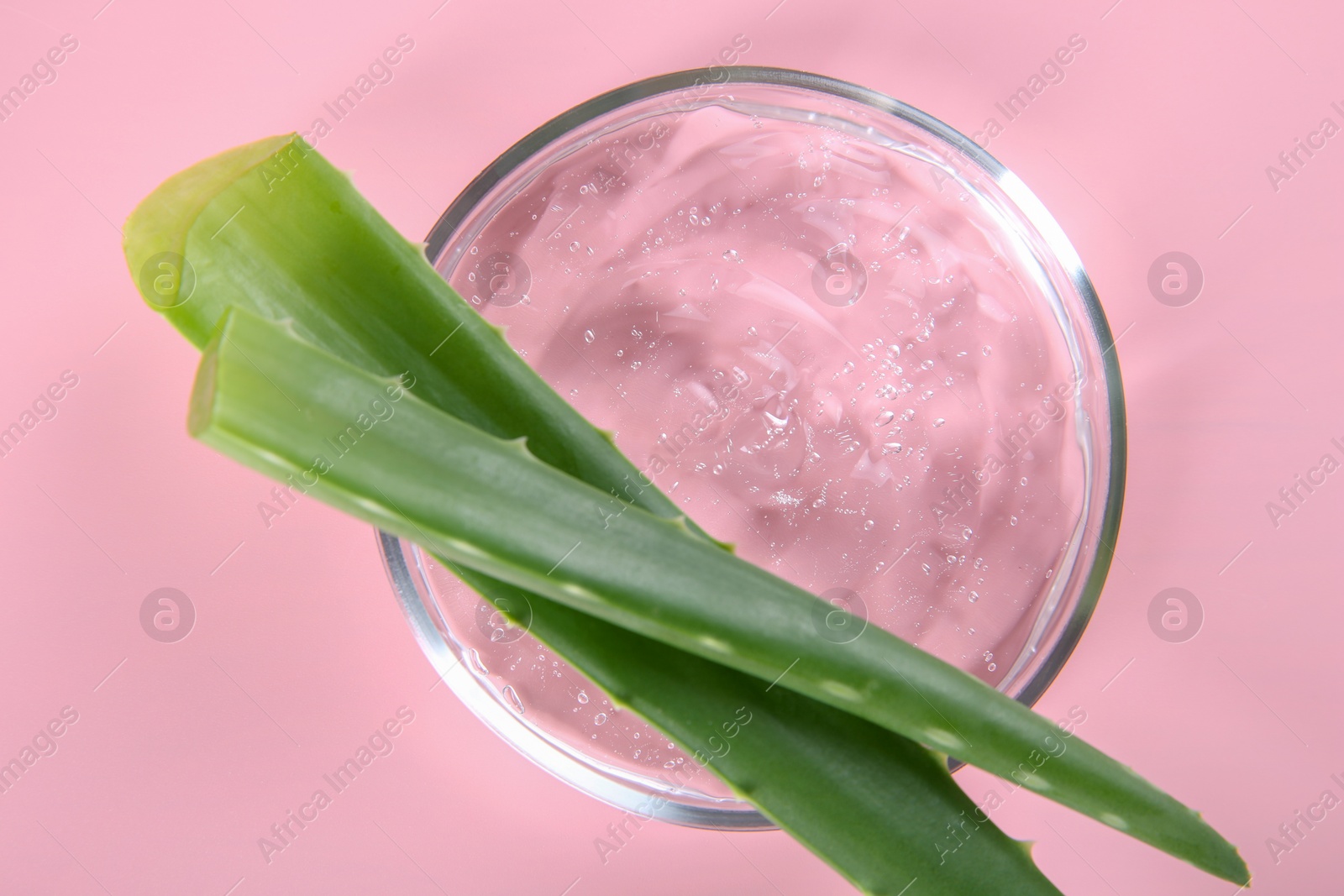 Photo of Aloe vera leaves and cosmetic gel on pink background, top view