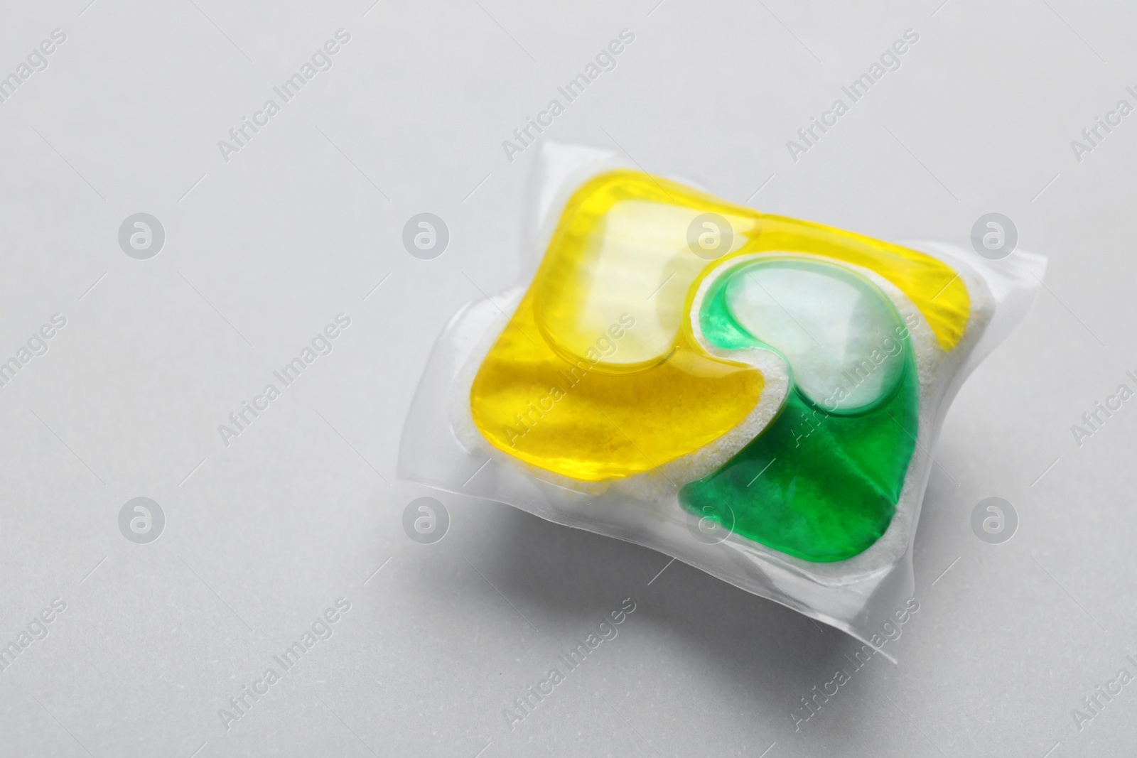 Photo of Dishwasher detergent pod on light grey background, closeup. Space for text