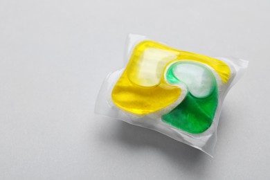 Photo of Dishwasher detergent pod on light grey background, closeup. Space for text