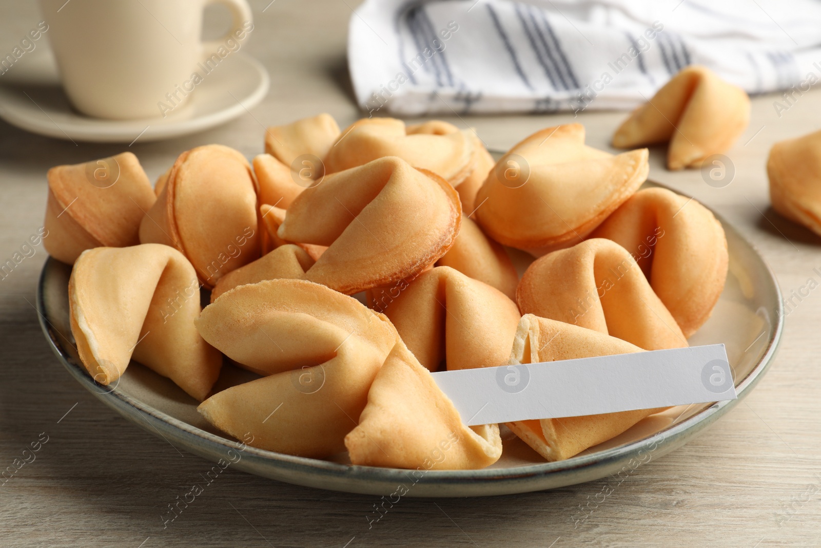 Photo of Tasty fortune cookies and paper with prediction on wooden table, closeup. Space for text