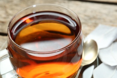 Aromatic tea in glass cup on wooden table, closeup