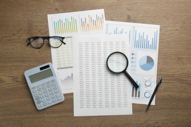 Photo of Accounting documents, magnifying glass, stationery and glasses on wooden table, top view