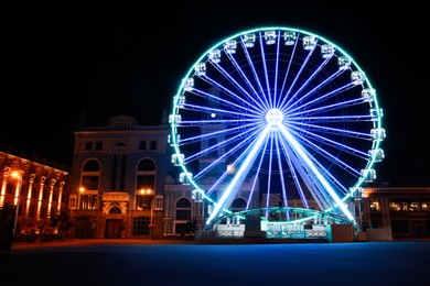 Photo of Beautiful glowing Ferris wheel on city street at night