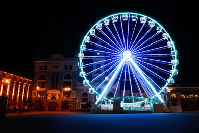 Beautiful glowing Ferris wheel on city street at night