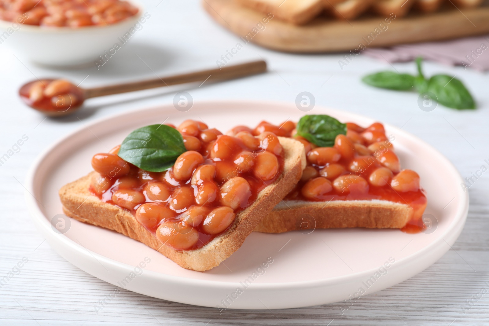 Photo of Toasts with delicious canned beans on white wooden table