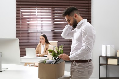 Photo of Dismissed man packing personal stuff into box in office