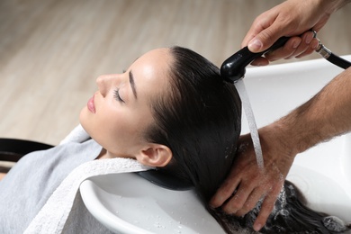 Photo of Stylist washing client's hair at sink in beauty salon