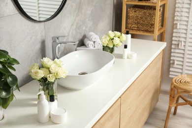 Photo of Beautiful roses and bath accessories near sink in bathroom