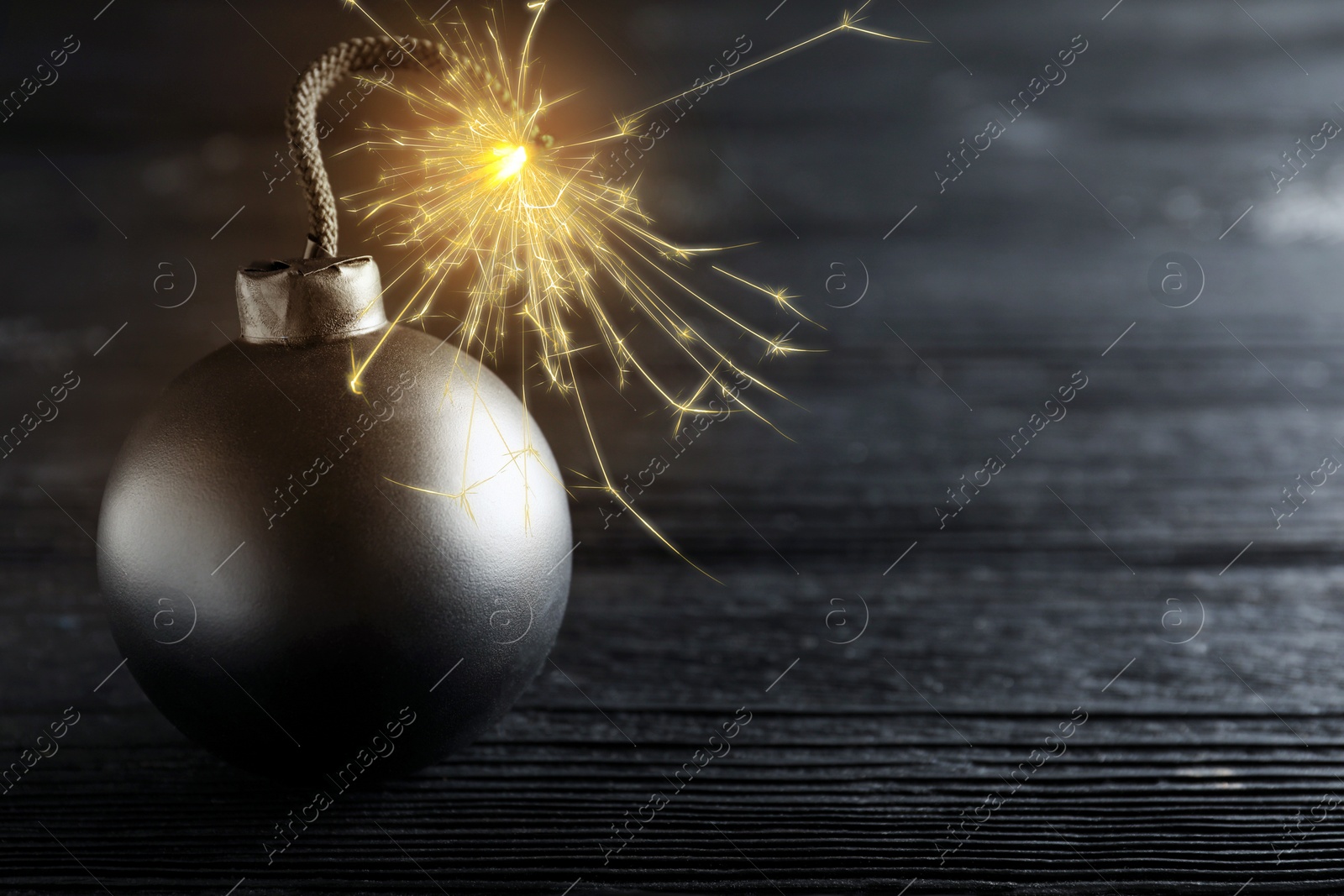 Image of Old fashioned bomb with lit fuse on black wooden table, space for text