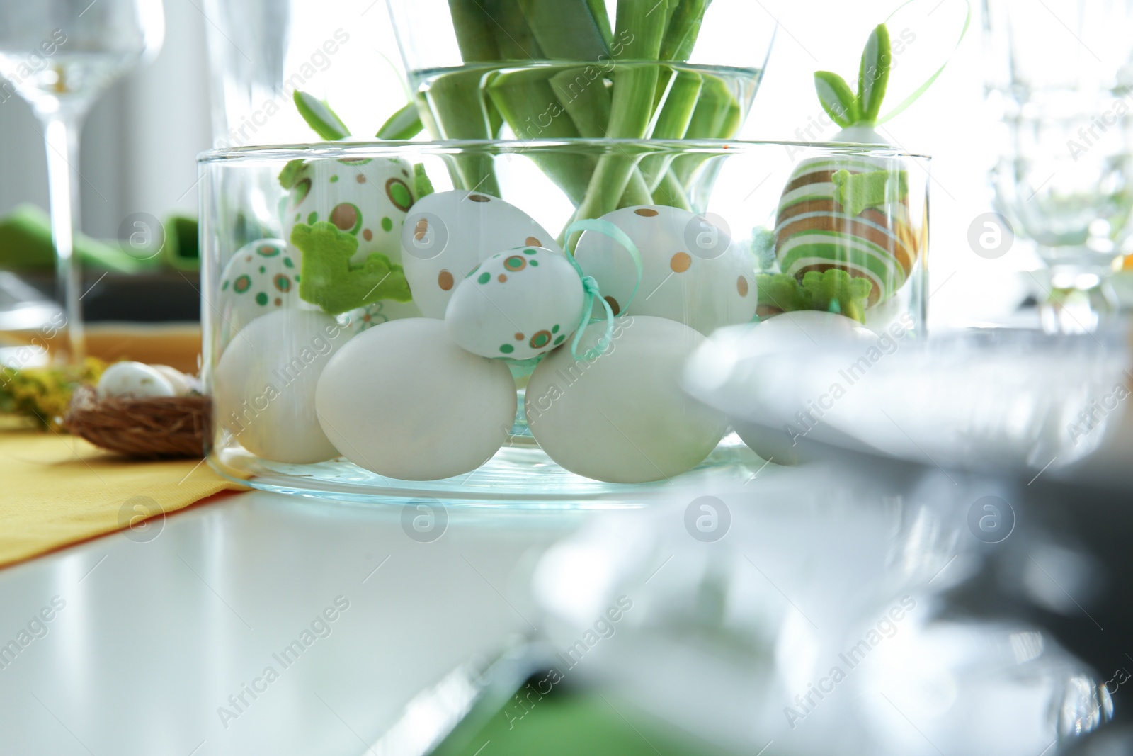 Photo of Festive table setting with Easter decorative eggs in bowl, closeup