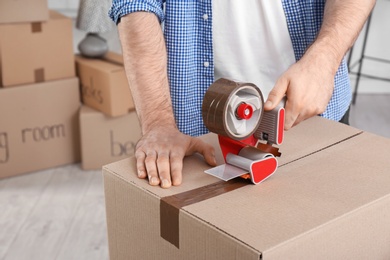 Photo of Man packing cardboard box indoors, closeup. Moving day