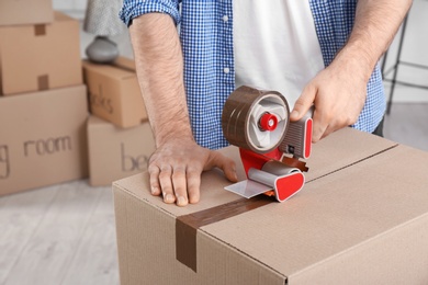 Man packing cardboard box indoors, closeup. Moving day