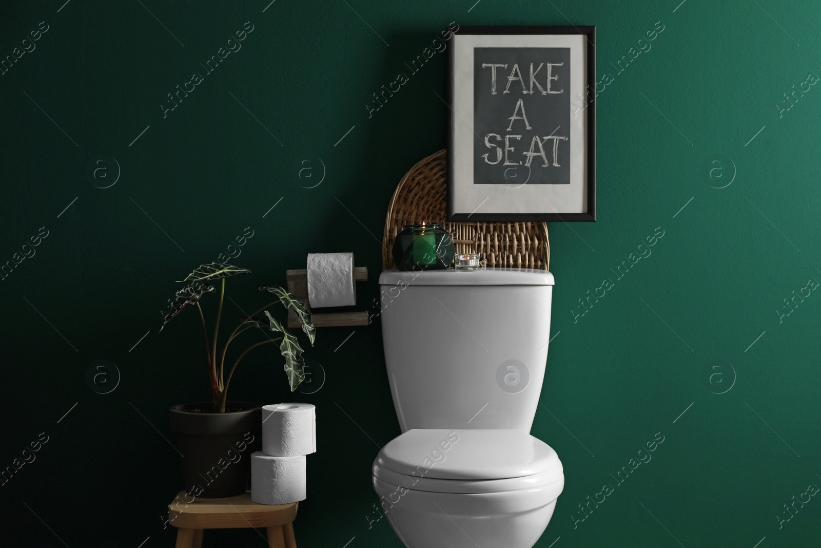 Photo of Decor elements, paper rolls and toilet bowl near green wall. Bathroom interior