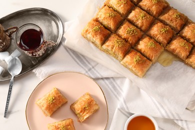 Delicious sweet baklava with pistachios served on white table, flat lay