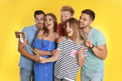 Photo of Happy young people taking selfie on yellow background