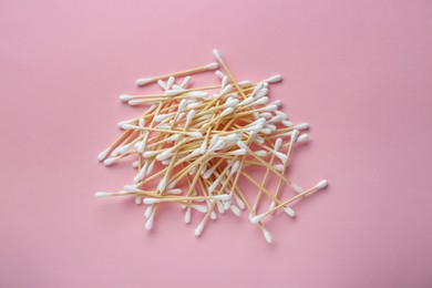 Photo of Heap of wooden cotton buds on pink background, flat lay