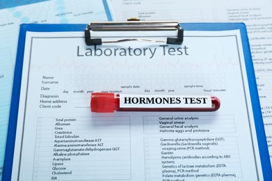 Photo of Hormones test. Sample tube with blood on clipboard with laboratory forms, top view