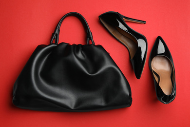 Stylish woman's bag and shoes on red background, flat lay