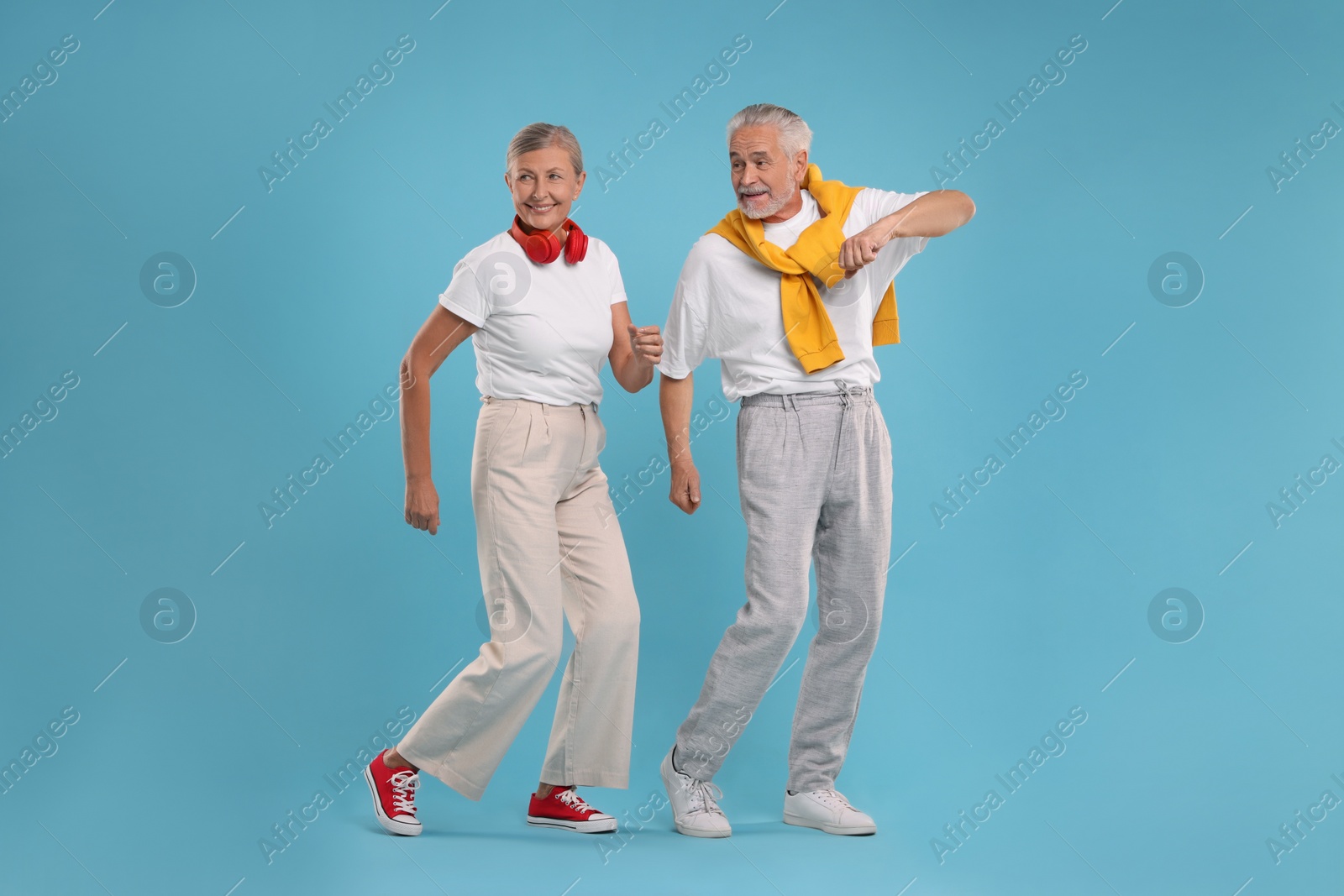 Photo of Senior couple dancing together on light blue background