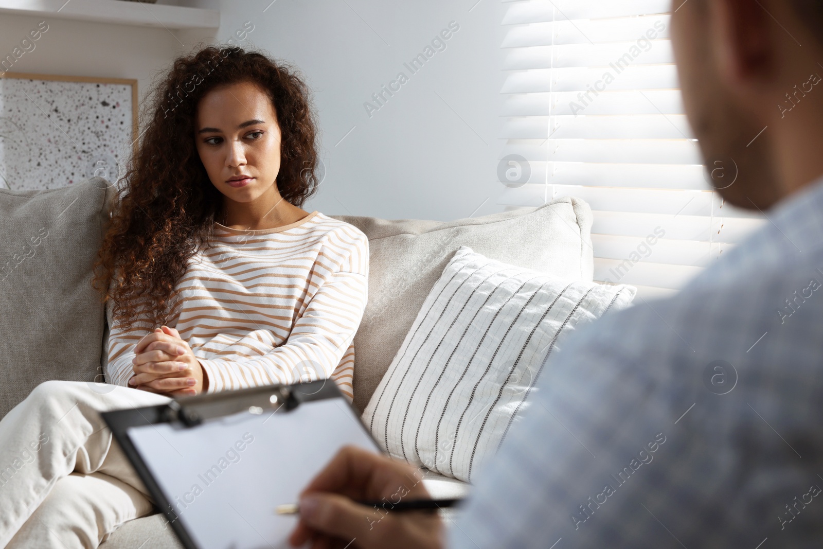 Photo of Unhappy African American woman having session with her therapist indoors