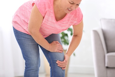 Senior woman suffering from knee pain at home, closeup