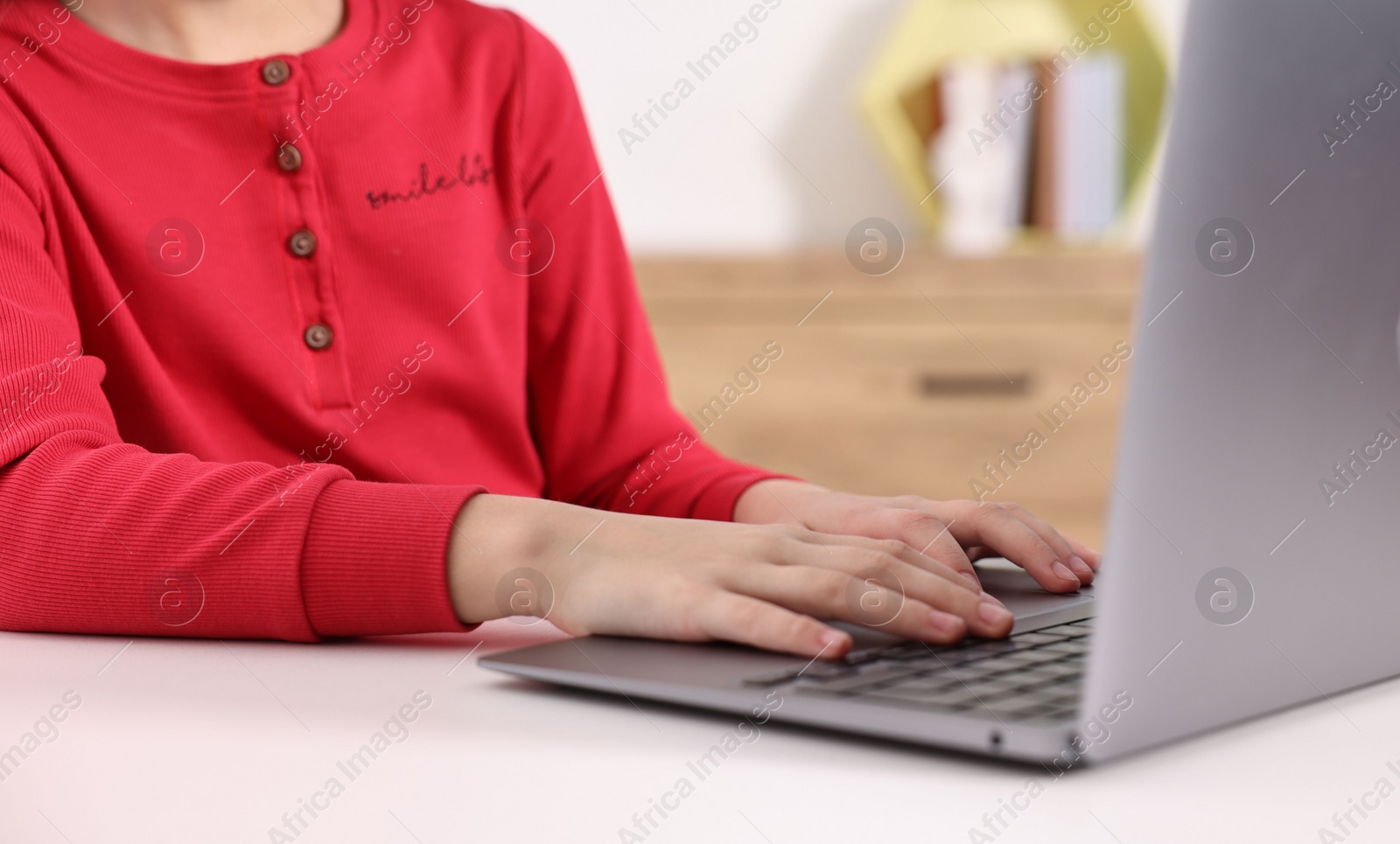 Photo of E-learning. Girl using laptop during online lesson at table indoors, closeup