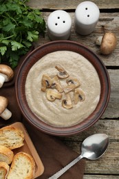 Delicious mushroom cream soup served on wooden table, flat lay