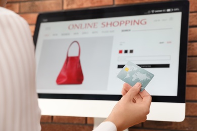 Photo of Woman with credit card using computer for online shopping indoors, closeup