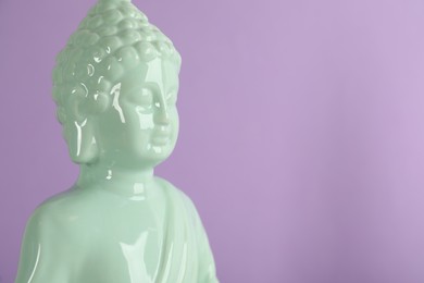 Photo of Beautiful ceramic Buddha sculpture on violet background. Space for text