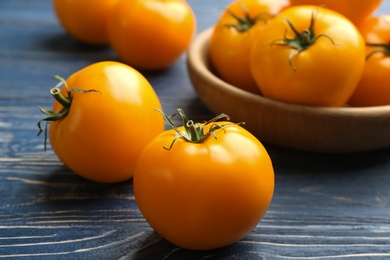 Photo of Ripe yellow tomatoes on blue wooden table, closeup