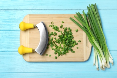 Composition with fresh green onions on light blue wooden background, top view