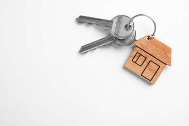 Photo of House keys with trinket on white background, top view. Space for text