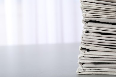 Photo of Stack of newspapers on grey table, space for text. Journalist's work