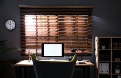 Stylish room interior with modern computer and comfortable office chair