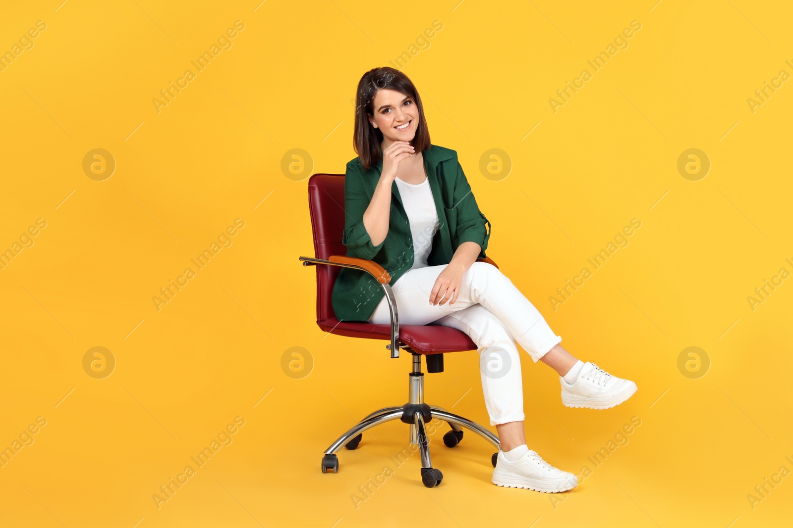 Photo of Young woman sitting in comfortable office chair on yellow background