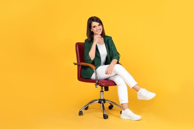 Young woman sitting in comfortable office chair on yellow background