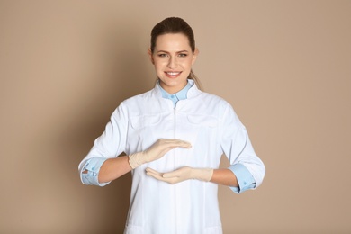 Female dentist holding something on color background