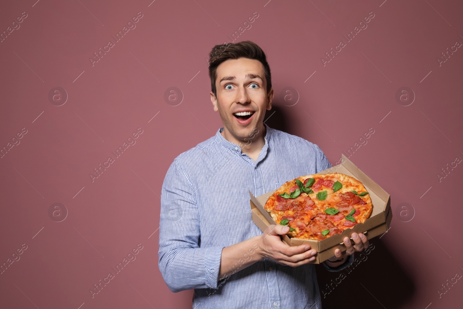 Photo of Attractive young man with delicious pizza on color background