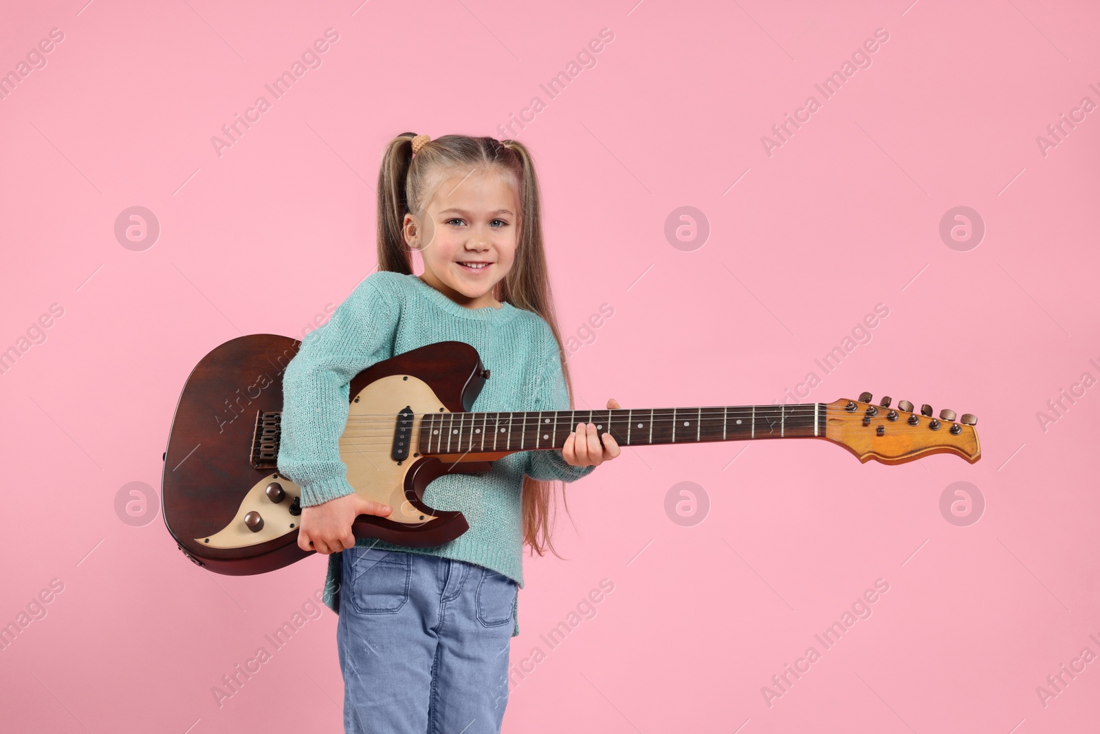 Photo of Happy girl with electric guitar on pink background. Space for text