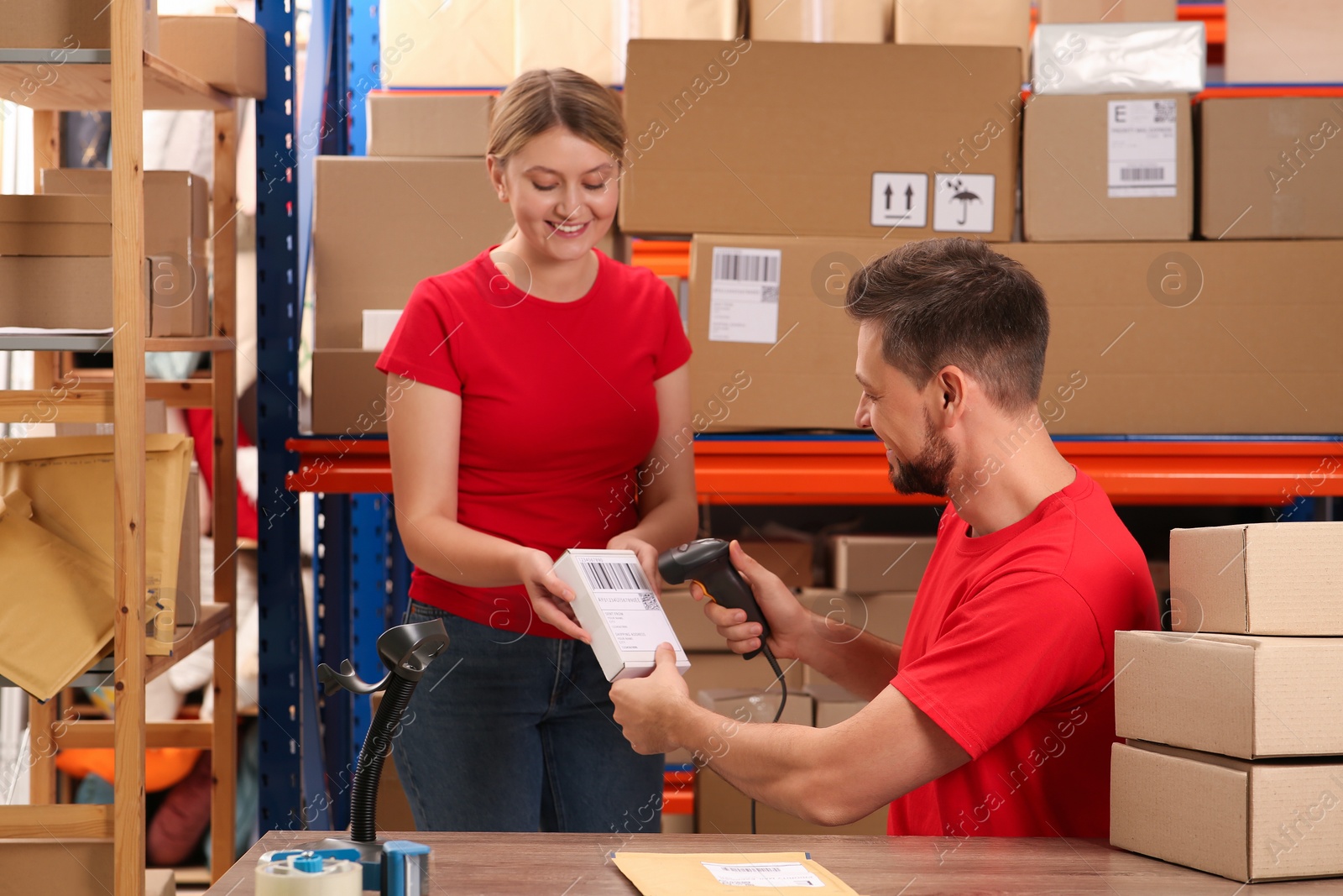 Photo of Post office workers with scanner reading parcel barcode indoors