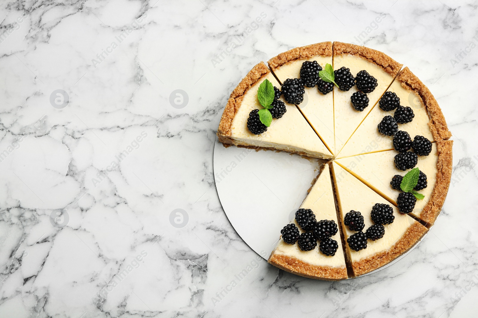 Photo of Sliced delicious cheesecake with blackberries on white marble background, top view. Space for text