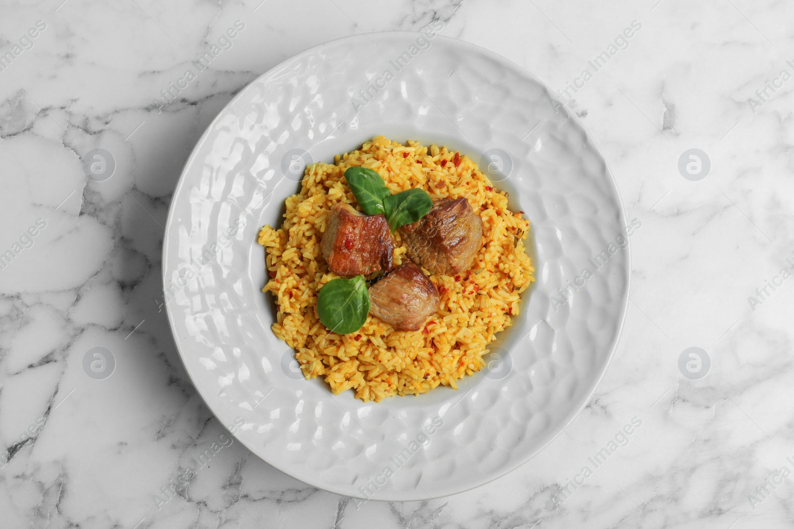 Photo of Plate with delicious rice pilaf on marble background, top view