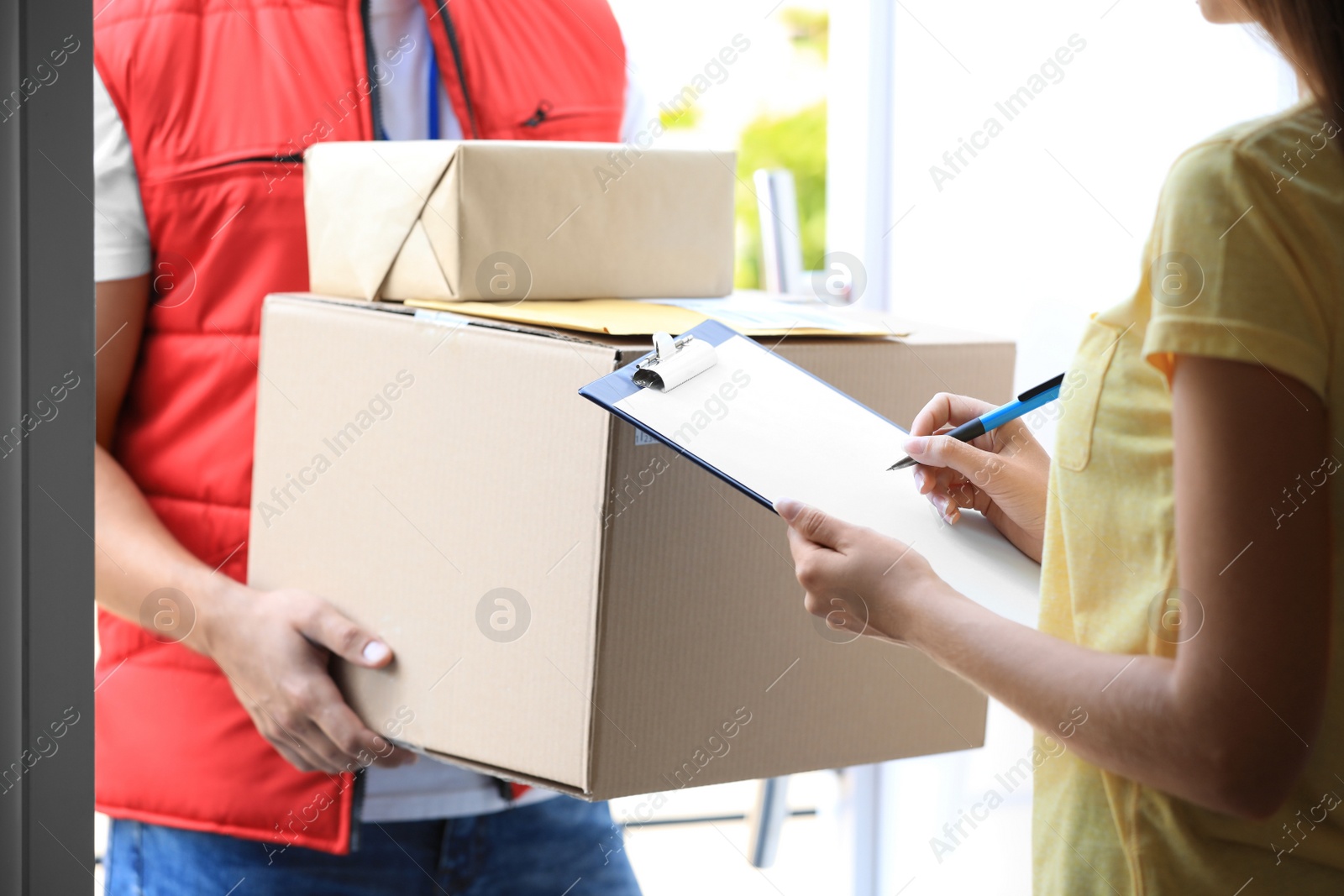Photo of Woman signing for delivered parcels on doorstep, closeup. Courier service