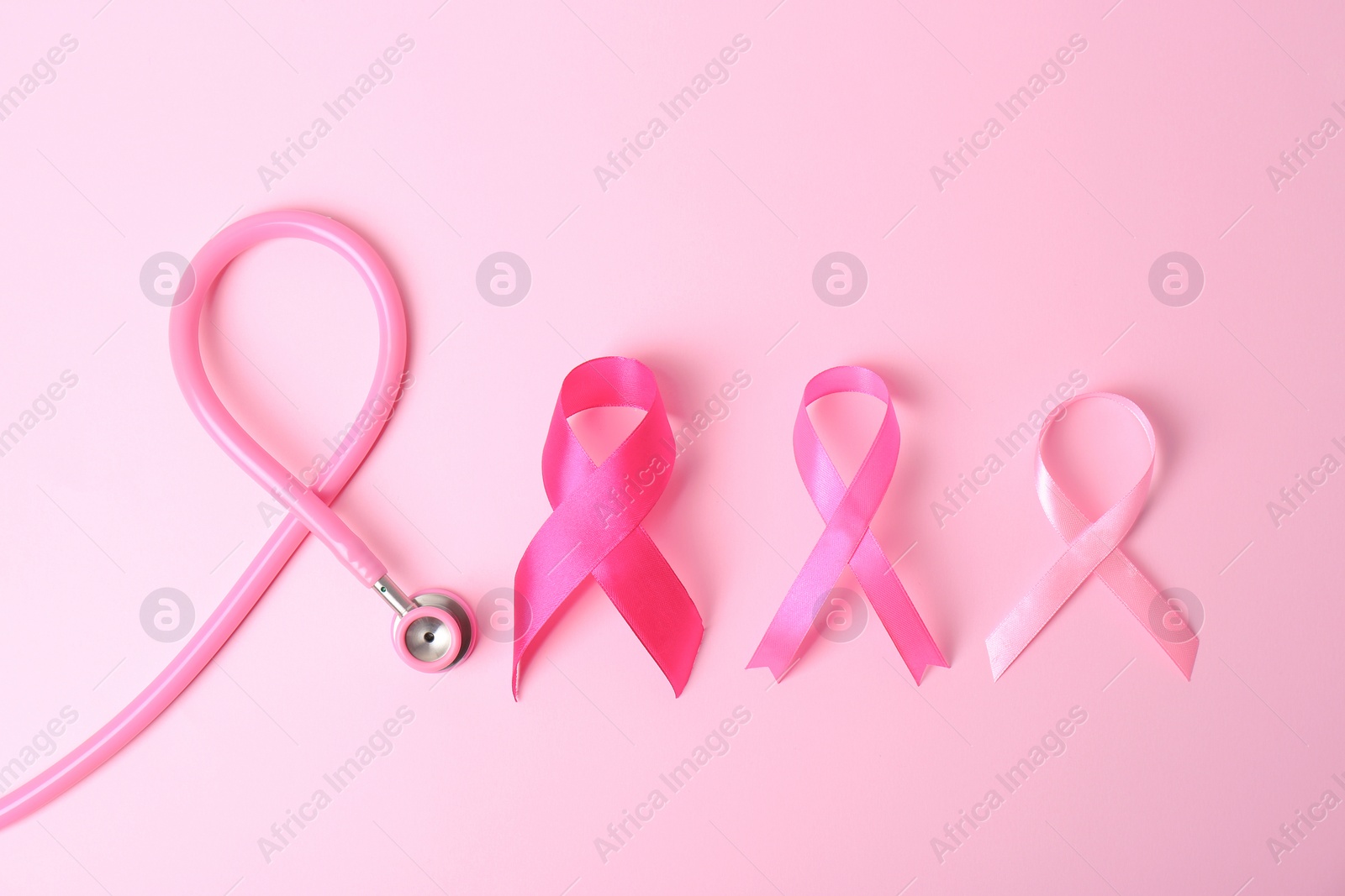 Photo of Pink ribbons with stethoscope on color background, top view. Breast cancer concept