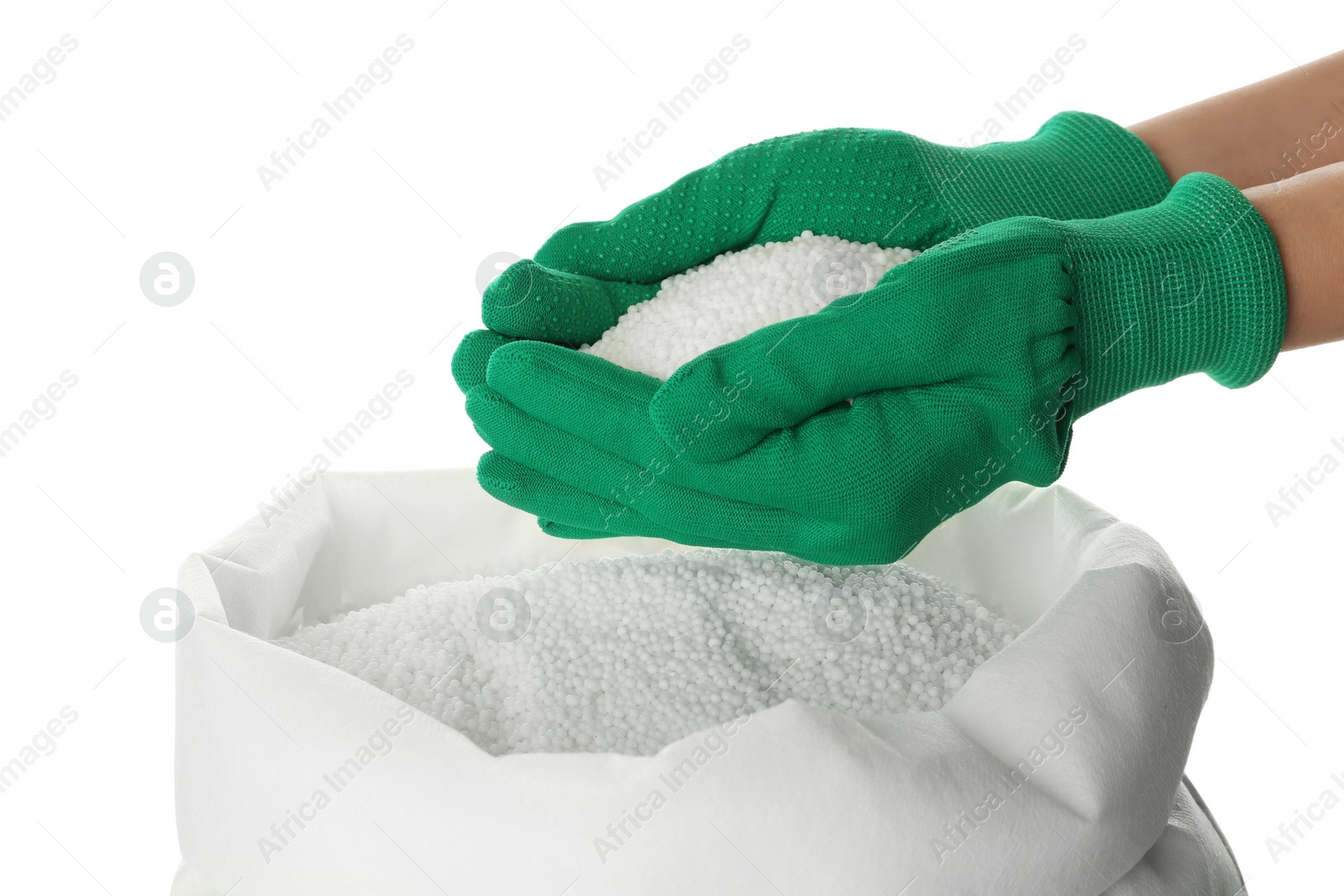 Photo of Man holding ammonium nitrate pellets above sack on white background, closeup. Mineral fertilizer