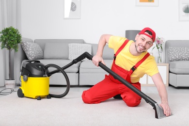 Photo of Mature man hoovering carpet with vacuum cleaner in living room